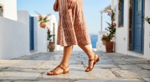 A stylish, editorial-quality shot of a modern woman's legs and feet showcasing a chic summer skirt p